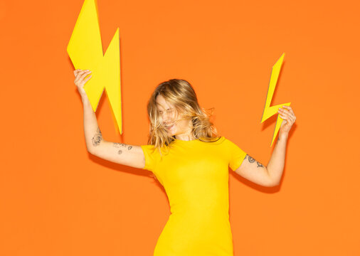 Model holding paper lightning bolt against orange background