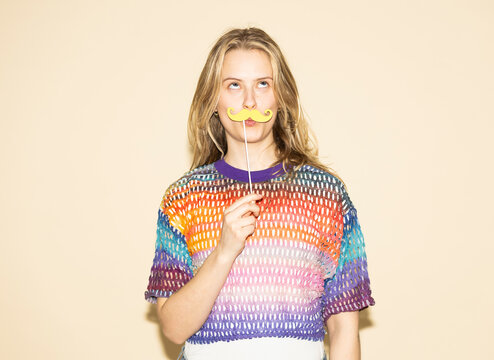 Silly portrait with a paper mustache and multi-colored sweater