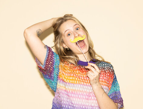 Smiling model with a fake mustache wearing a multi colored sweater