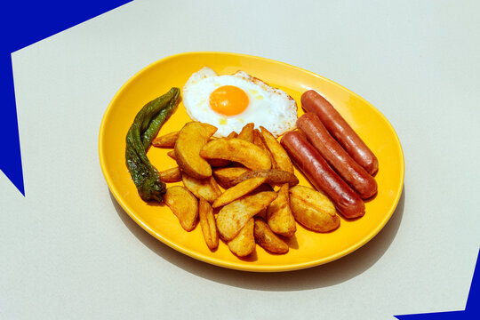 Fried egg sausage and potato wedge on yellow plate