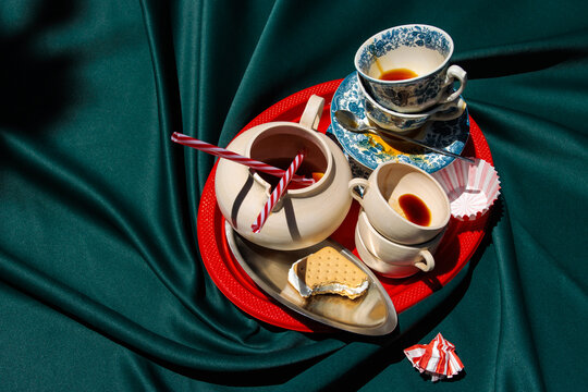 Messy coffee cups and bitten cookie on red tray over green fabric