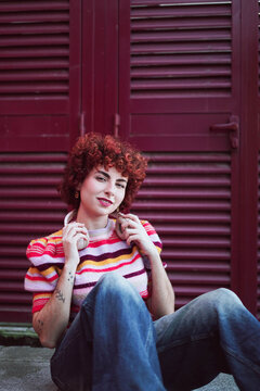 Redhead with headphones sitting outdoors looking at camera