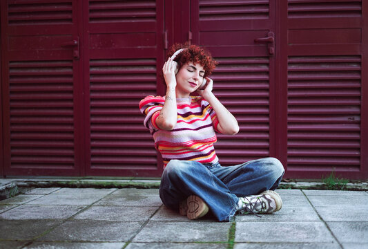 Redhead sitting outdoors listening to music