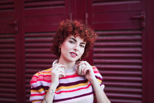 Redhead wearing striped sweater holding headphone outdoor