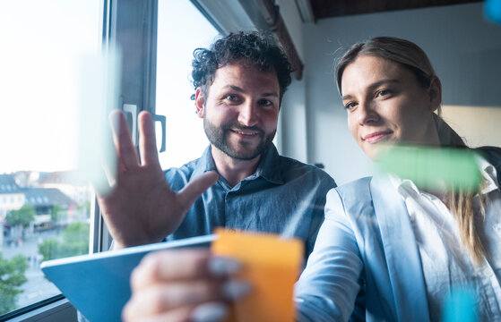 Colleague brainstorming with sticky note and tablet in office