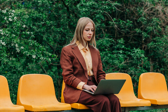 Businesswoman in suit working on laptop outdoors in park