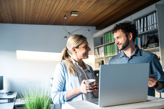 Smiling colleagues discussing work at the office desk