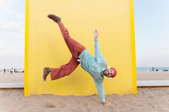 Energetic superhero flying in handstand pose on Barcelona beach