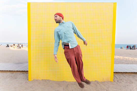 Energetic hero flying by yellow tiled wall on Barcelona beach
