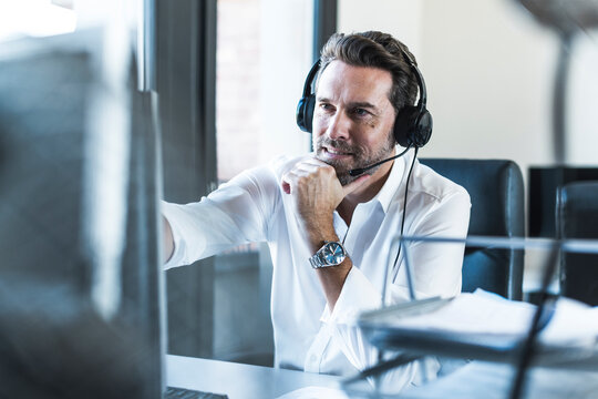 Businessman with headset looking at computer in office