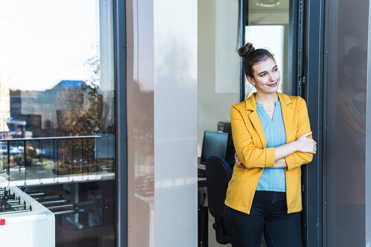 Smiling businesswoman standing at the office door taking a break