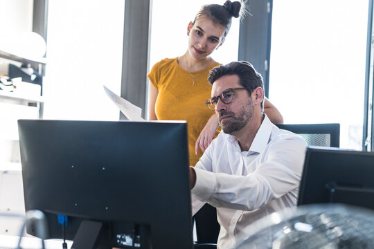 Colleagues discussing document at the office computer
