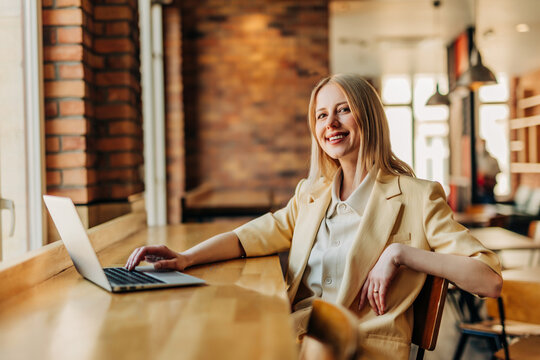 Smiling businesswoman working on a laptop at a modern office cafe