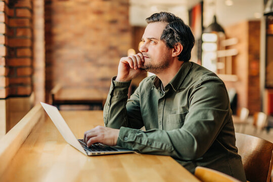 Businessman thinking while working on laptop in office cafe