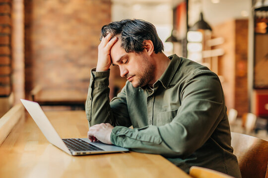 Tired businessman working on a laptop in an office cafe