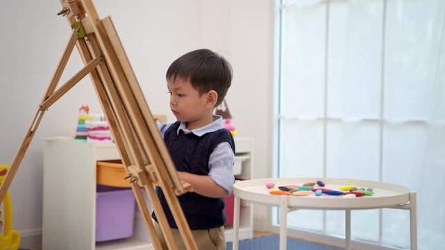 Little boy drawing on an easel, developing imagination, creativity, and artistic skills in early childhood
