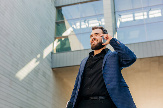 Smiling businessman talking on smartphone outside office building