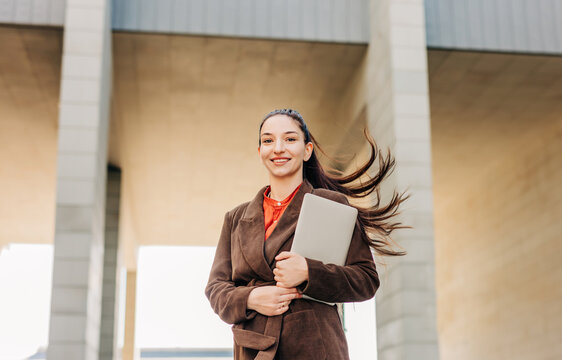Confident businesswoman holding laptop outdoors