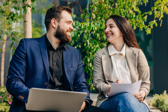 Smiling businessman and businesswoman working outdoors