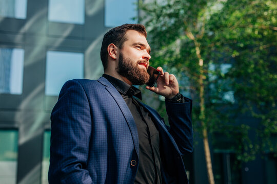Boss in suit walking outdoors talking on smartphone