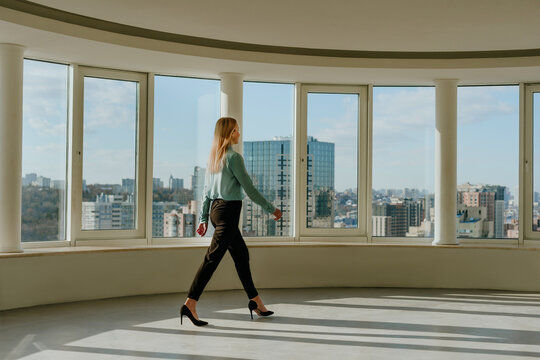 Businesswoman walking in modern empty office with city skyline view