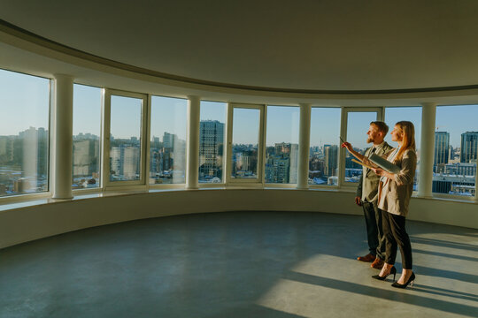 Realtor and investor discussing empty office with urban view
