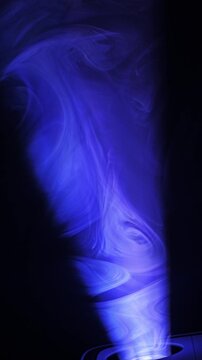 Projector light ray piercing atmospheric smoke, building dramatic volumetric glow against dark background.
