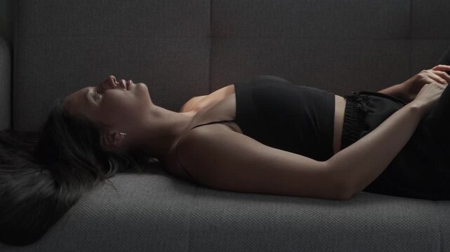 Young woman lying on sofa and staring at ceiling in silence, depression, emotional emptiness, apathy, loneliness and loss of purpose in modern life concept