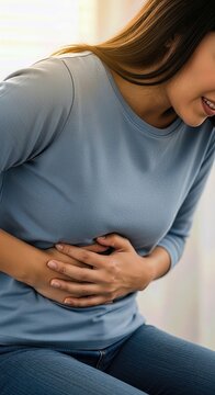 Unhappy female experiencing acute abdominal pain, sharp stomach ache, digestive distress, symptoms of potential gallbladder disease, serious health condition requiring treatment