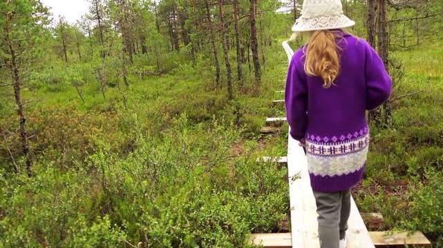 Little beautiful girl walks on swamp in Estonia