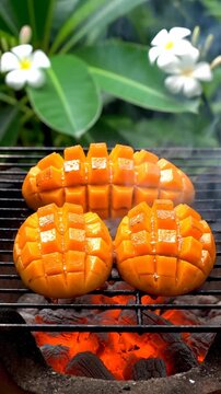 Grilled mangoes are sizzling on a barbecue surrounded by flowers outdoors