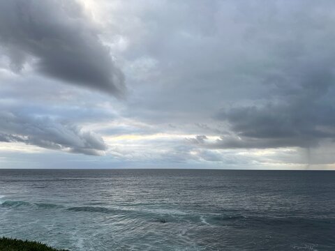 A view of the gray, overcast sky hanging over the rolling waves of the Pacific Ocean at La Jolla, California.