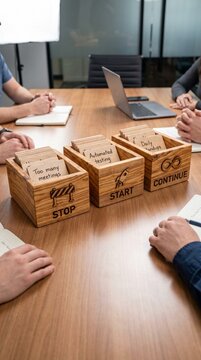 Agile Retrospective meeting format concept with stop start continue wooden bins on a conference table during a business meeting