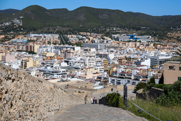 Obraz premium «Ibiza, Spain»; May 26 2026: Scenic panoramic view from the historic Baluarte de Sant Jordi fortress wall in Dalt Vila old town, overlooking the white houses of Ibiza city and the blue horizon 