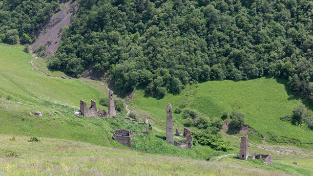 Scenic view of the medieval Khiani tower complex ruins on green mountain slopes, Ingushetia, Russia, with stone watchtowers and forested hills in summer