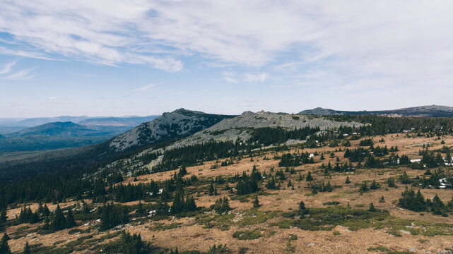 Wide mountain landscape of Bolshoy Iremel with rocky ridge and conifer forest under cloudy sky near Tyulyuk, Bashkortostan, Russia, scenic Ural nature