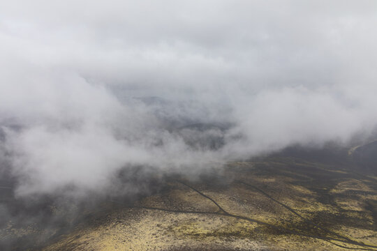 Low clouds and fog drift above volcanic lava fields and barren tundra in the Northern Breakthrough area, Tolbachinsky Dol, Kamchatka Krai, Russia