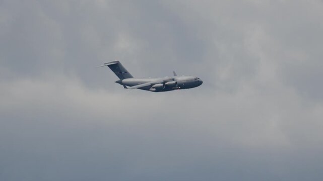 C-17 Globemaster performs cargo transport maneuver in overcast sky. Aircraft showcases military logistics capabilities during troop transport mission.