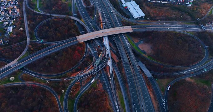 Aerial view of a complex highway junction, Woodbridge, New Jersey. Elevated perspective of interlocking road ramps and multi lane freeways surrounded by evening woods.