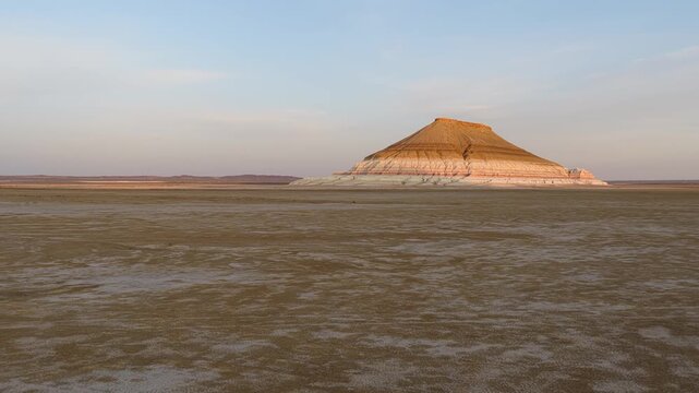 Aerial view of Mount Bokty with its unique layered geological formations rising from the flat desert floor in Karakiya District, Mangystau Region, Kazakhstan.