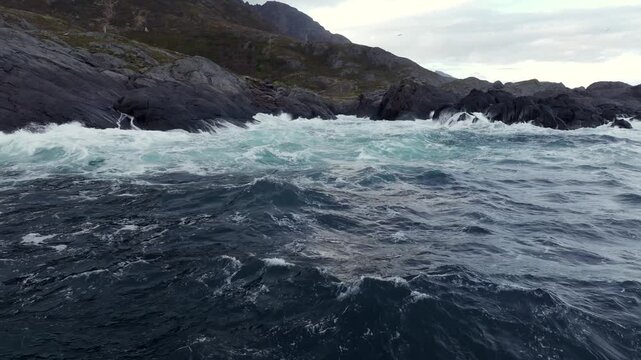 Rough coastal seascape with waves crashing on dark rocky shoreline