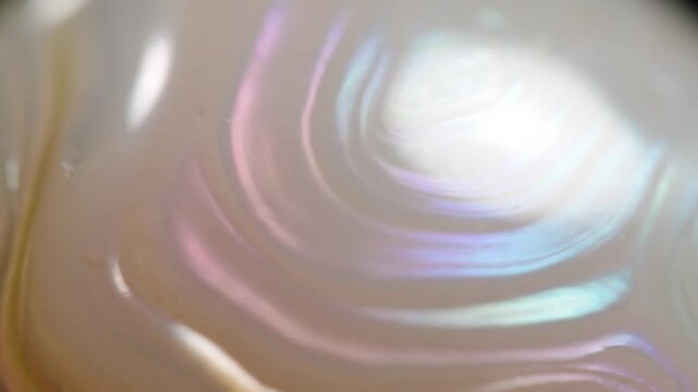 Close-up of the iridescent, swirling patterns on the surface of a mother of pearl shell.