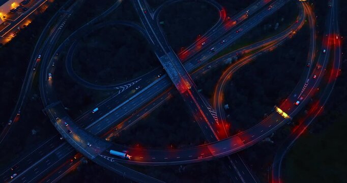 Highway loop ramps with vehicle light trails, United States. Top down abstract graphic composition showing overlapping concrete overpasses, vibrant red and white long exposure lines.