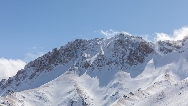 Winter landscape of rugged snow-covered mountains under a clear blue sky in Alay Valley, Osh Region, Kyrgyzstan, ideal for travel, nature and adventure themes
