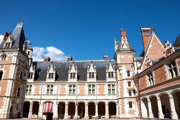 Fototapeta premium Beautiful inner courtyard of Royal Chateau de Blois in summer, with ornate French Renaissance and Gothic arches, columns, colorful facades, and unrecognizable tourists, Loire Valley, France