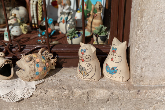 Kotor, Montenegro - July 31, 2025: Close-up of handmade ceramic cat figurines and pottery souvenirs displayed on a stone windowsill in Kotor, Montenegro, in warm sunlight