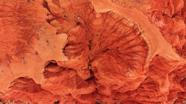 Overhead drone view of red sandstone erosion patterns, Spain. Top down perspective of fan shaped ridges and crevices in vivid orange rock.