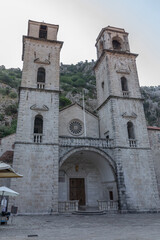 Fototapeta premium Kotor, Montenegro - August 11, 2025: Front view of St. Tryphon Cathedral with stone arch entrance and twin bell towers in Kotor, Kotor Municipality, Montenegro, historic Romanesque church landmark