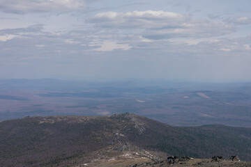 Obraz premium Wide panoramic landscape view from Konzhakovsky Stone in the Northern Urals, Sverdlovsk Oblast, Russia, with forested hills, rocky ridge and clouds