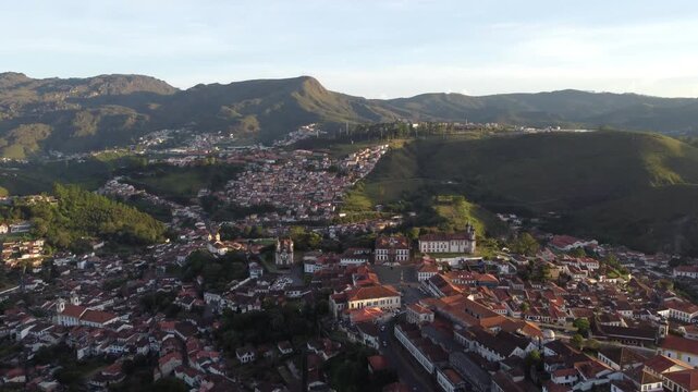 Aerial views of Ouro Preto, Brazil, at sunset, featuring the historic colonial town, iconic churches, rolling mountains, traditional architecture, and the warm light of the golden hour.